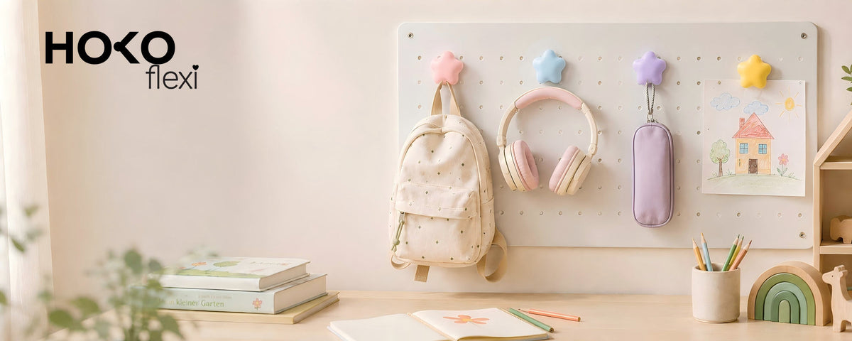 Bunte Sternmagnete am HOKO-flexi Pegboard mit Rucksack, Kopfhörern, Mäppchen und Kinderzeichnung.